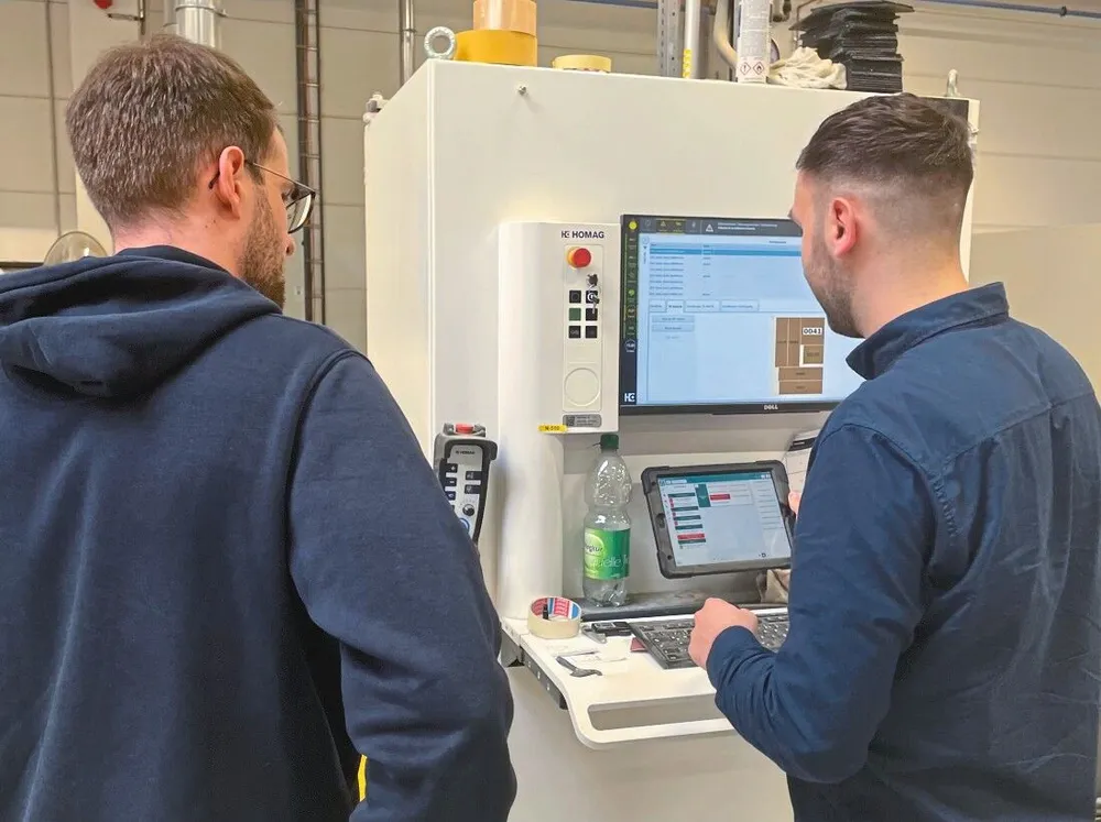 Zwei Mitarbeiter von Hengelhaupt an einer Maschine in der Werkstatt, einer mit Artesa auf dem Tablet
