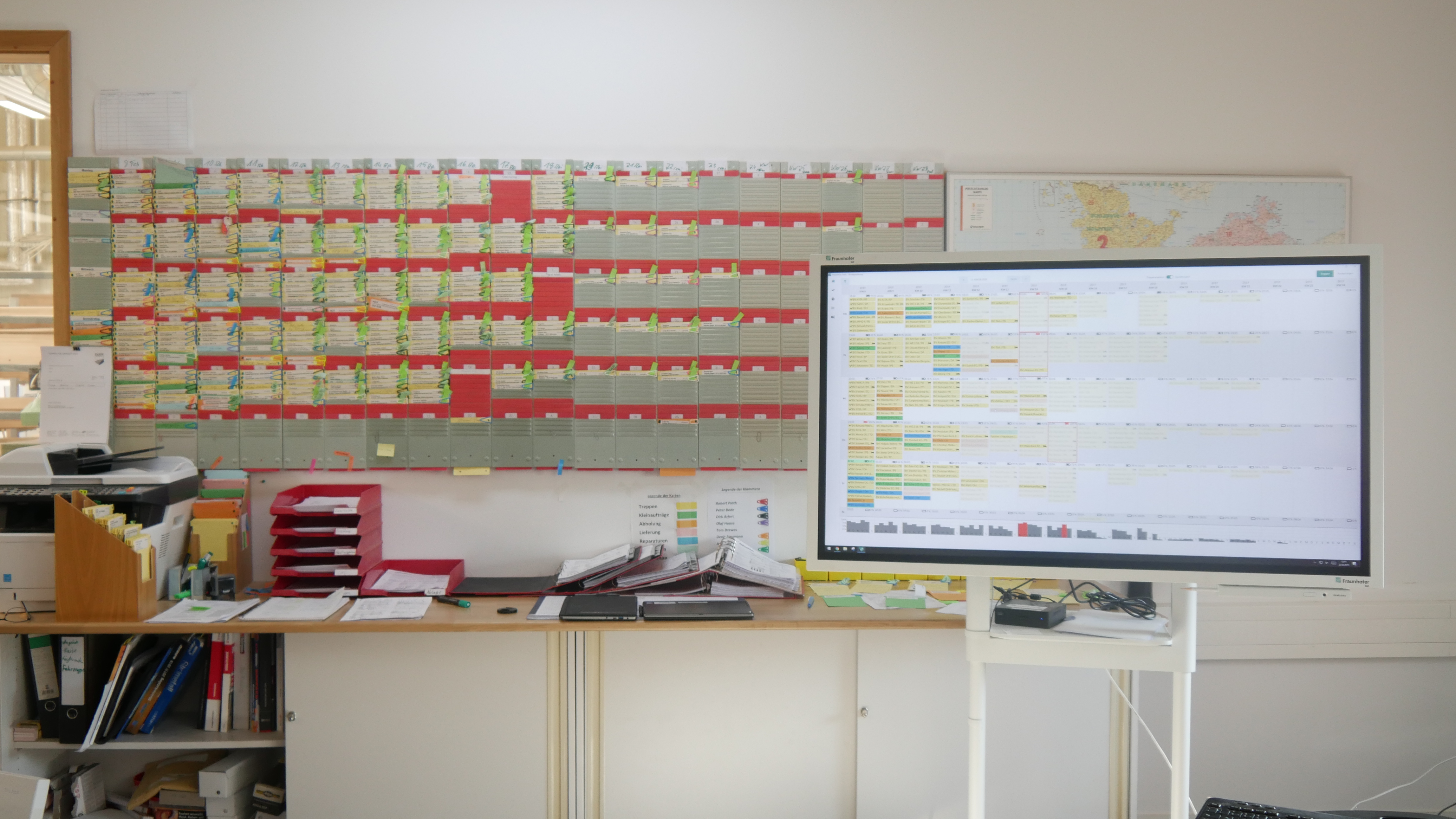 Analoge Steckkarten-Tafel neben dem Monitor mit der digitalen Plantafel im Büro bei Treppenbau Plath
