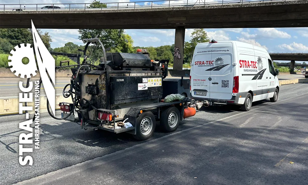 Maschinenanhänger und Firmenwagen von STRA-TEC unter einer Autobahnbrücke
