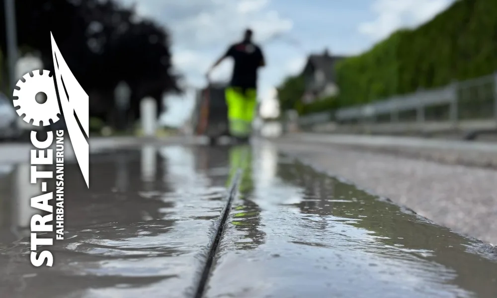 Frischer Nassschnitt in einer Fahrbahn, im Hintergrund ein Mitarbeiter von STRA-TEC