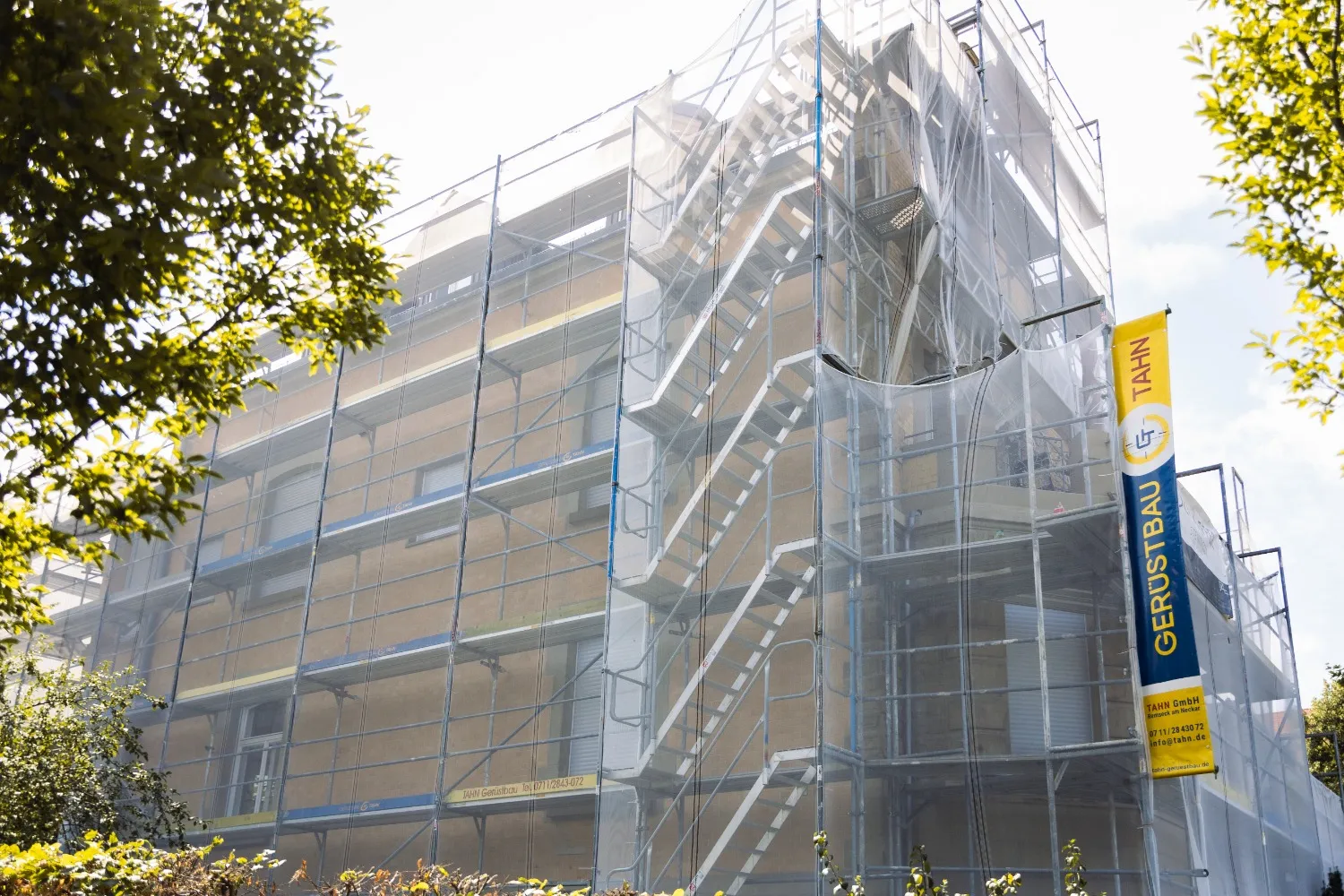 Eingerüstetes Altbau-Wohnhaus von Tahn Gerüstbau mit Treppenturm und Schutznetz